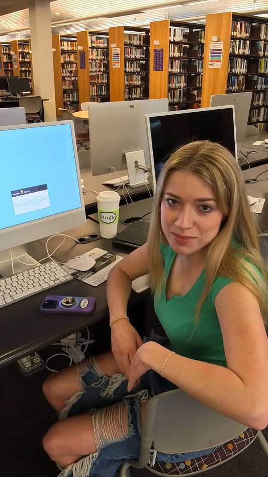 Cassidee in the computer lab with a Single® Medium Sticker on her coffee mug and a Single® Small Sticker on her phone.