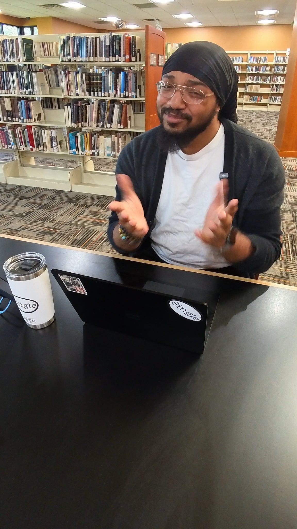 Dwight in the library with a Single® Medium Sticker on his tablet, and on his tumbler.
