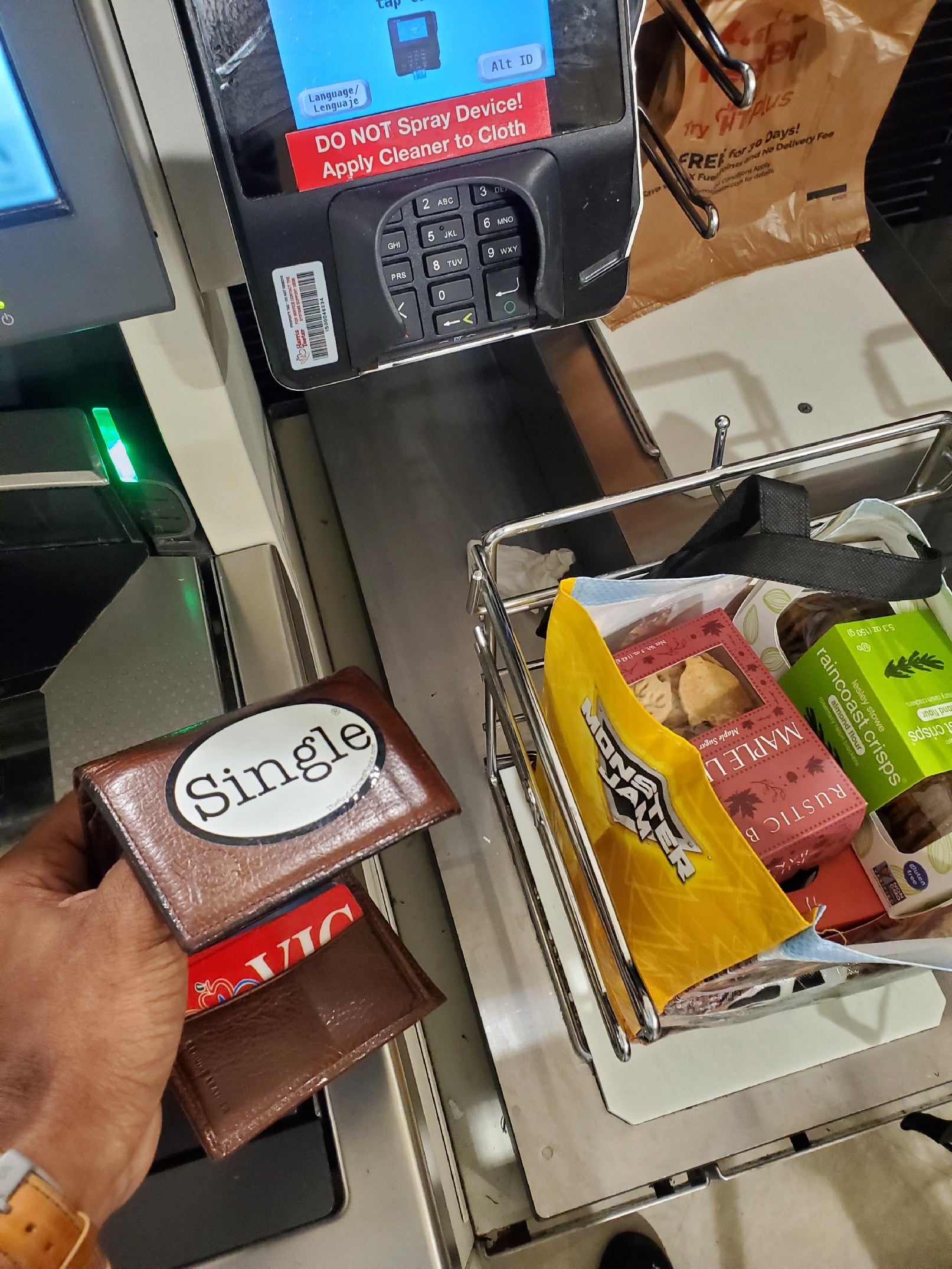 Jason shows that he is member of the Single® community with a Single® Medium Sticker on his wallet while checking out at the grocery store.
