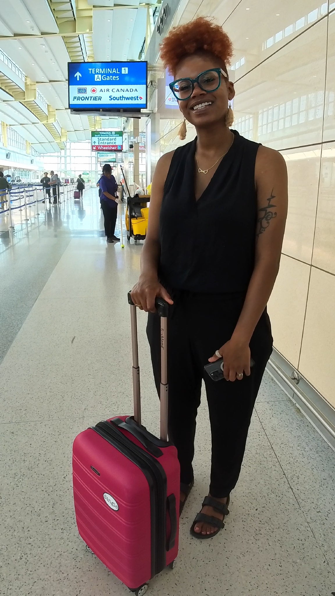 Kayla strolls through the airport with a Single® Medium Sticker on her luggage.